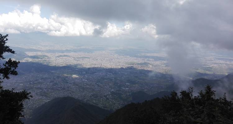 Luftaufnahme einer Stadtlandschaft mit Wolkendecke und Bergen.