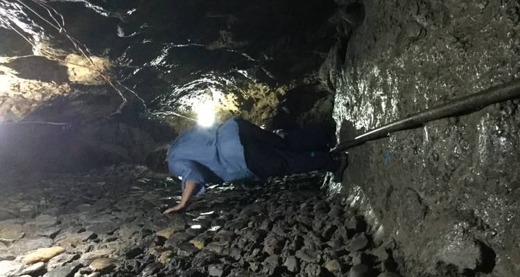 Persoon die een donkere, rotsachtige grot verkent.