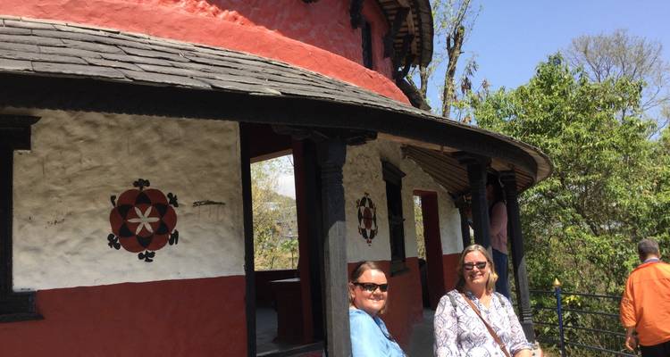 Mensen die buiten zitten bij een rood en wit gebouw met traditioneel ontwerp.