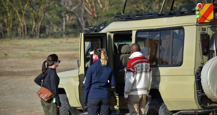 Groep mensen bij een safarivoertuig, zich voorbereidend op een reis.
