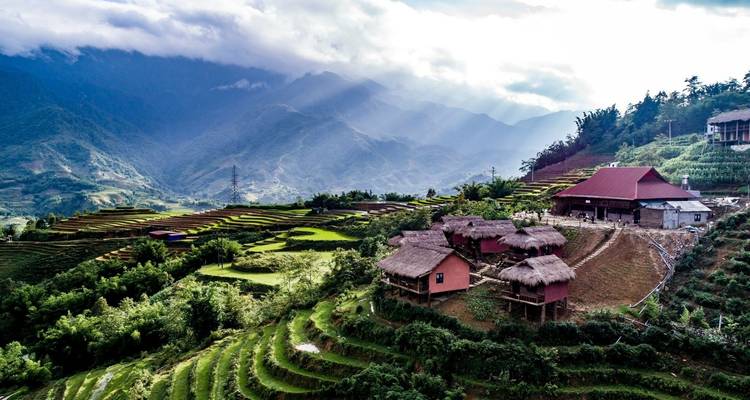 Terrassenfelder mit Häusern und bergiger Kulisse in Sapa.