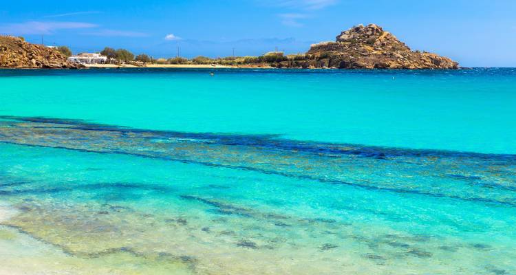 Mer turquoise claire avec une petite île rocheuse au loin.