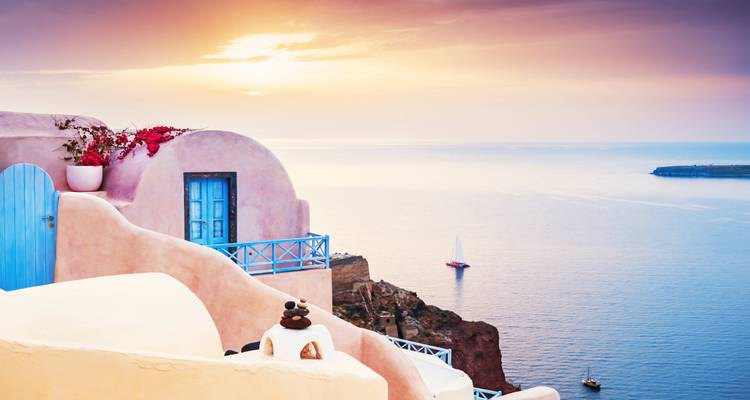 Scenic view of white buildings above the sea with sunset skies.