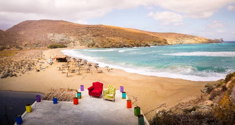 Una playa desierta con muebles coloridos frente al mar.