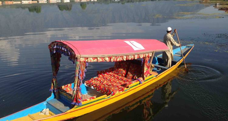 Homme ramant dans un bateau traditionnel sur un lac.