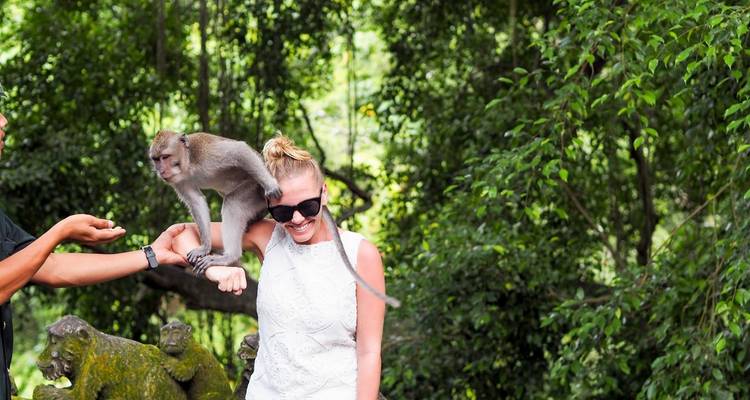 Femme avec un singe sur l'épaule dans un décor de forêt.