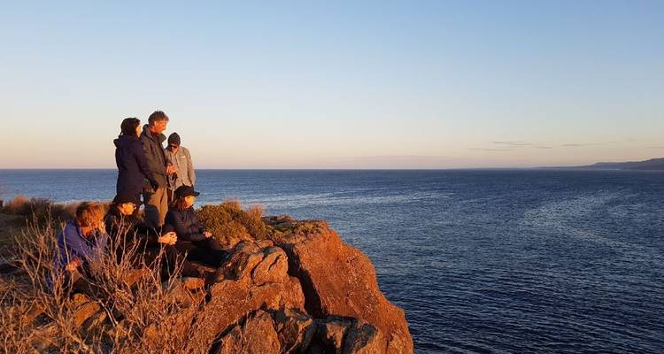 Menschen genießen einen malerischen Blick auf das Meer bei Sonnenuntergang.
