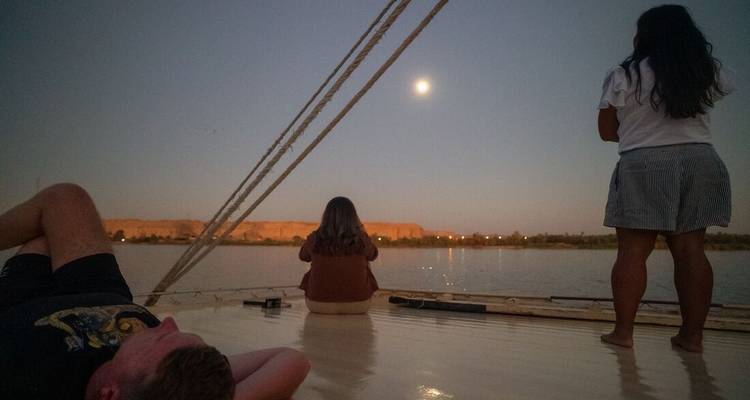 People on a boat watching the moon rise over the river.