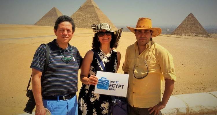Group of people with tour sign in front of pyramids.