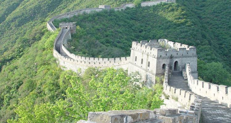 Die Große Mauer von China, die sich durch grüne Hügel windet.