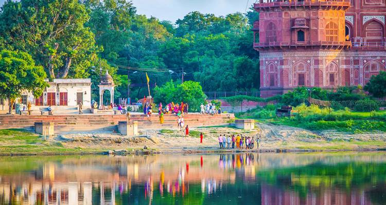 Mensen die genieten van een uitzicht aan de rivier met een rood bakstenen gebouw.