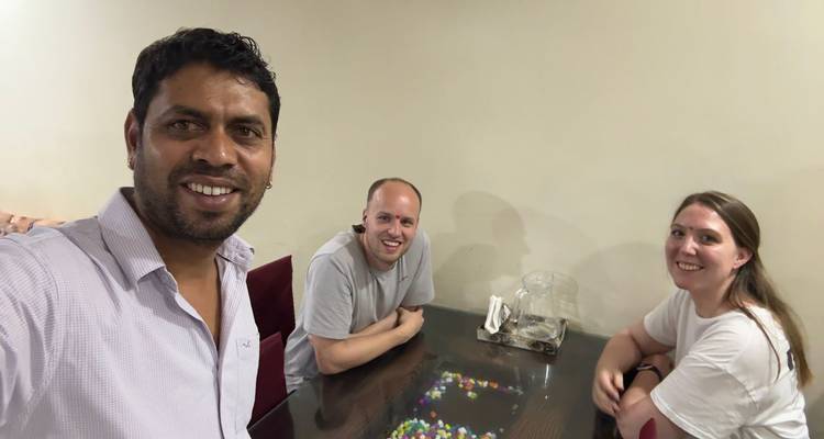 Drei Personen sitzen an einem Tisch in einem Raum.