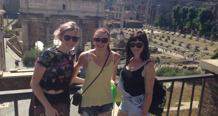 Trois personnes posant avec des ruines en arrière-plan.