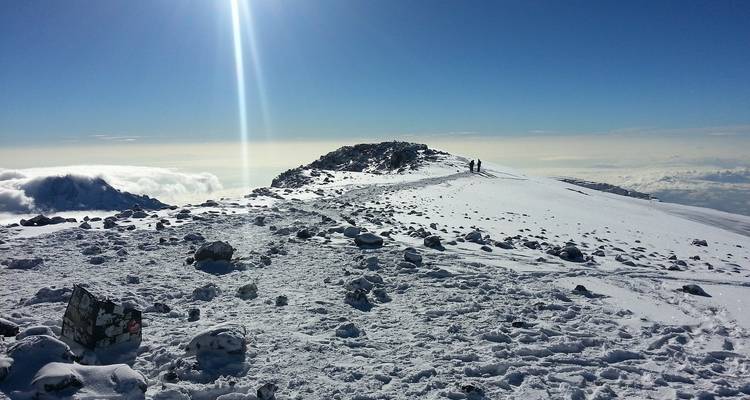Snowy mountain terrain with hikers in the distance