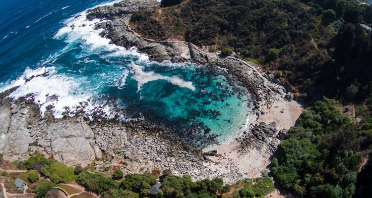 Vista aérea de una costa rocosa con una bahía turquesa cristalina
