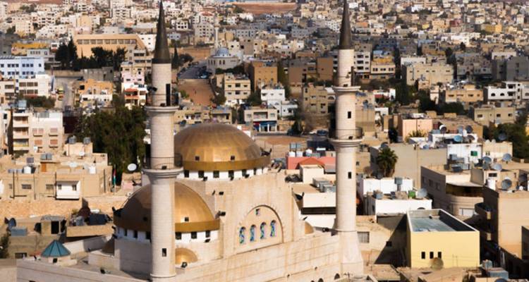 Une mosquée avec deux minarets dans un paysage urbain.