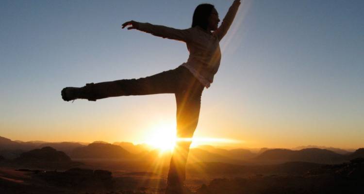 Silhouette of a person stretching at sunrise.