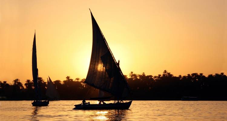 Sailing boats on a river during sunset.
