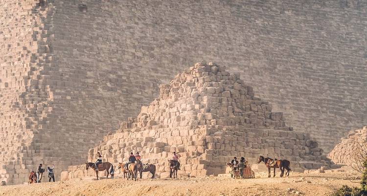 Des gens à cheval chevauchent près d'une pyramide.