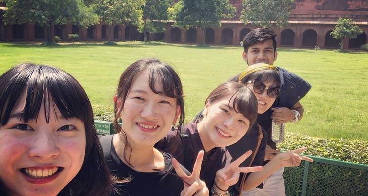 Gruppenselfie in einem Garten mit einem historischen Gebäude im Hintergrund.