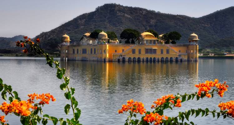 Jal Mahal rodeado de agua y flores vibrantes en primer plano.