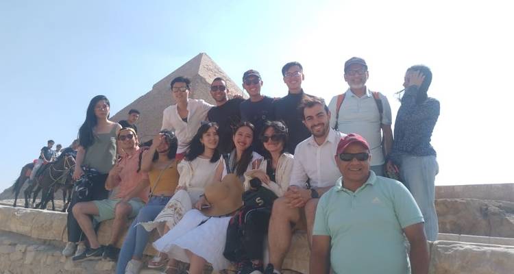 Große Gruppe von Menschen, die mit einer Pyramide im Hintergrund posieren.