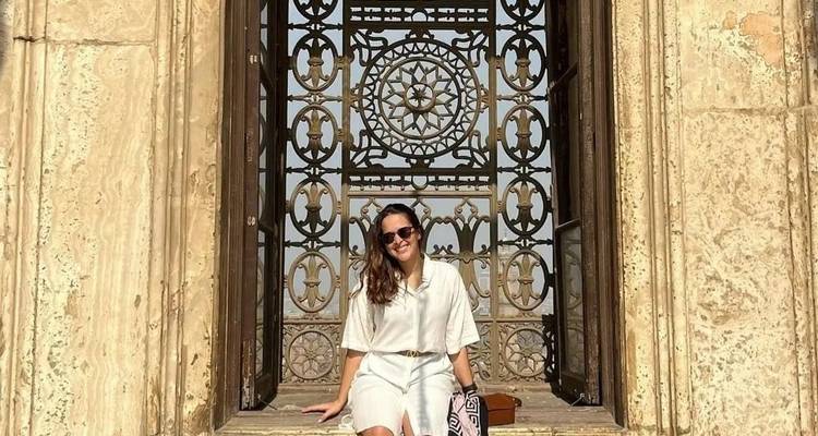 Frau, die in einem großen verzierten Fensterrahmen sitzt.