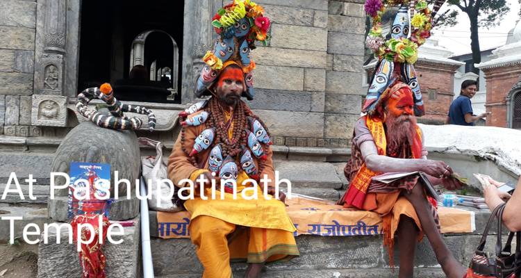 Farbenfrohe Sadhus in verziertem Kopfschmuck sitzen außerhalb eines Tempels mit überlagerte Textbezeichnung