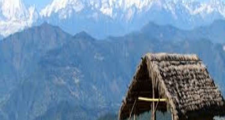 Hütte mit Strohdach vor einer Bergkette.