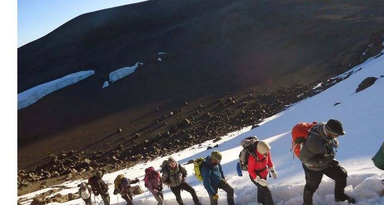Wanderer, die einen schneebedeckten Hang hinaufsteigen.