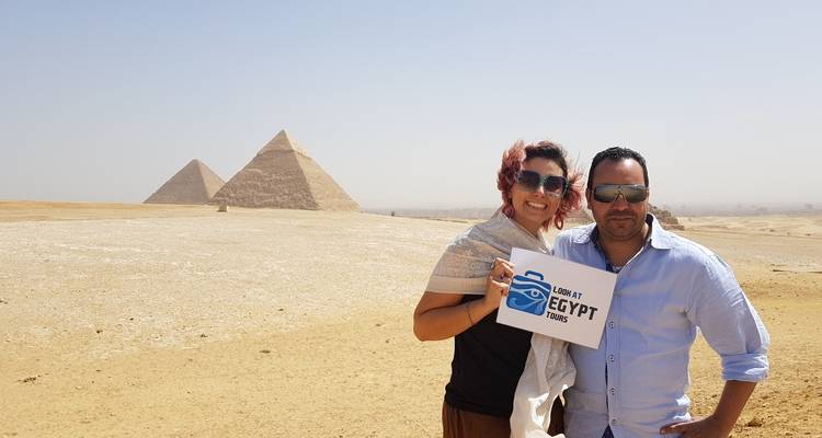 Tourists posing with a sign in front of the Pyramids.