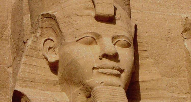 Primer plano de la cara colosal de piedra del Faraón Ramsés II con detalles de un fino trabajo de escultura.