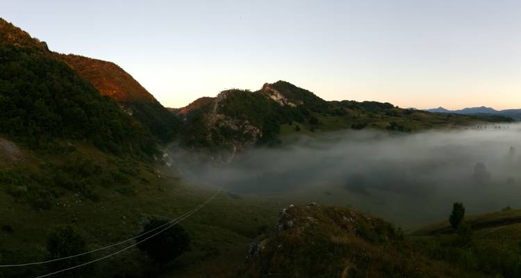 Une vue de vallée brumeuse sous un ciel de petit matin.