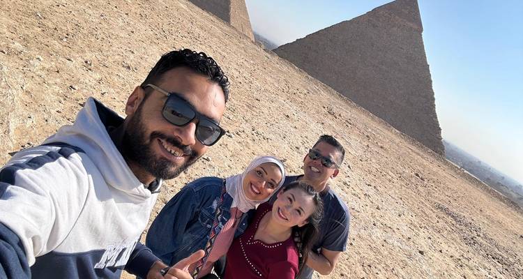 Gruppenselfie mit lächelnden Gesichtern und Pyramiden im Hintergrund.