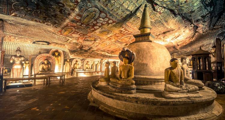 Interior de un templo cueva con estatuas y pinturas.