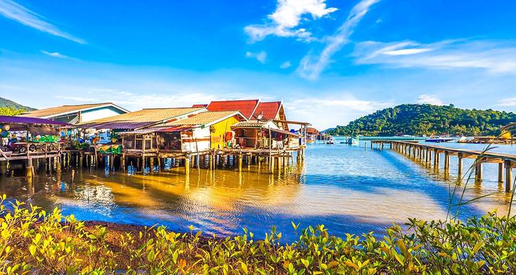 Kleurrijke huizen aan het water met een berg op de achtergrond.