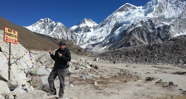 Wanderer posiert mit 'Way to Everest B.C.'-Schild vor Bergkulisse.