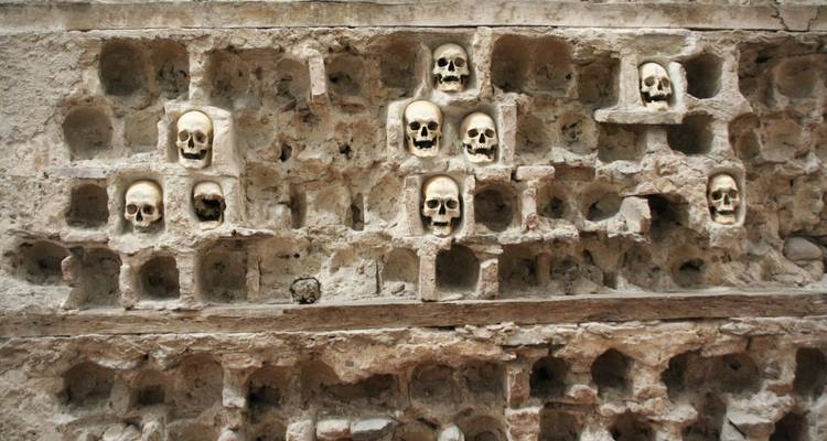 Collection of skulls in niches of an ancient structure.
