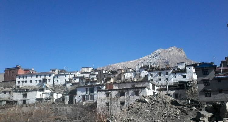 Häuser an einem Hang mit Bergen im Hintergrund.