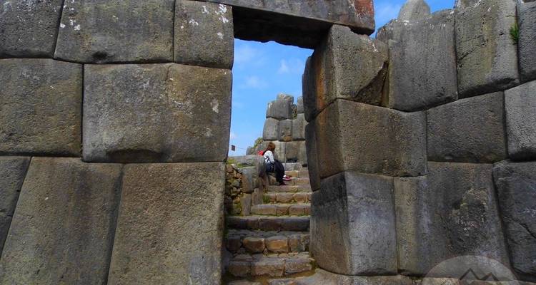 Alte Steinmauer mit sitzender Person im Eingang.