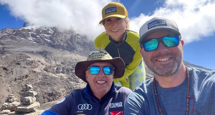 Trois personnes posant avec une vue sur la montagne en arrière-plan.