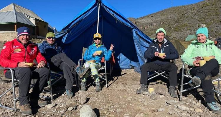 Camping en groupe, assis devant une tente.