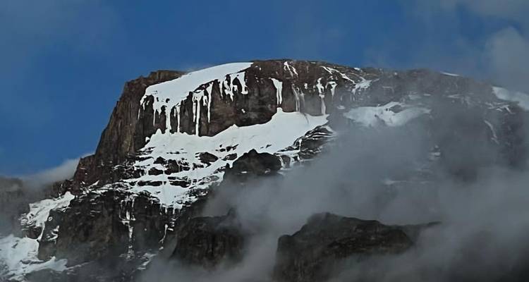 Snow-capped mountain partially covered in clouds.