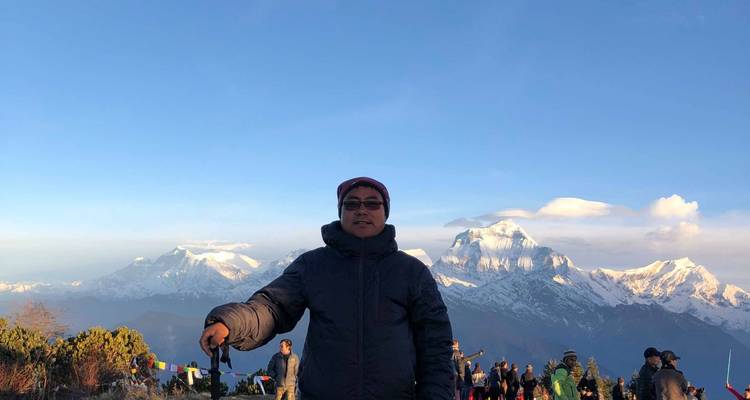 Persona de pie con montañas nevadas al fondo.