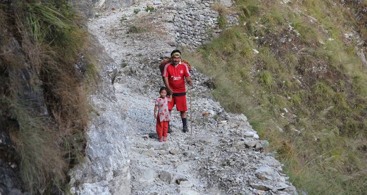 Een man en een kind lopen over een rotsachtig bergpad.
