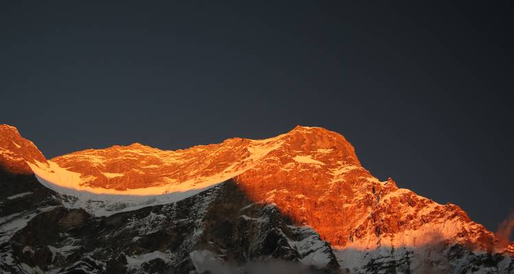 Een bergtop met een oranje gloed bij zonsopgang of zonsondergang.