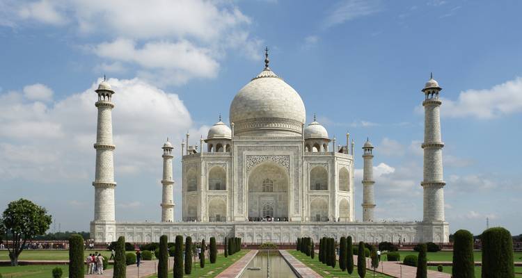 Iconic Taj Mahal amid formal gardens under a bright blue sky.