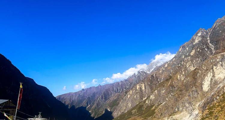 Ruig Himalaya-dal met steile rotsachtige hellingen onder een diepblauwe lucht.