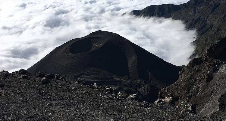 Een vulkanische krater omringd door een zee van wolken.