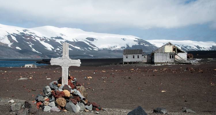 Edificios antiguos de madera con montañas cubiertas de nieve al fondo.